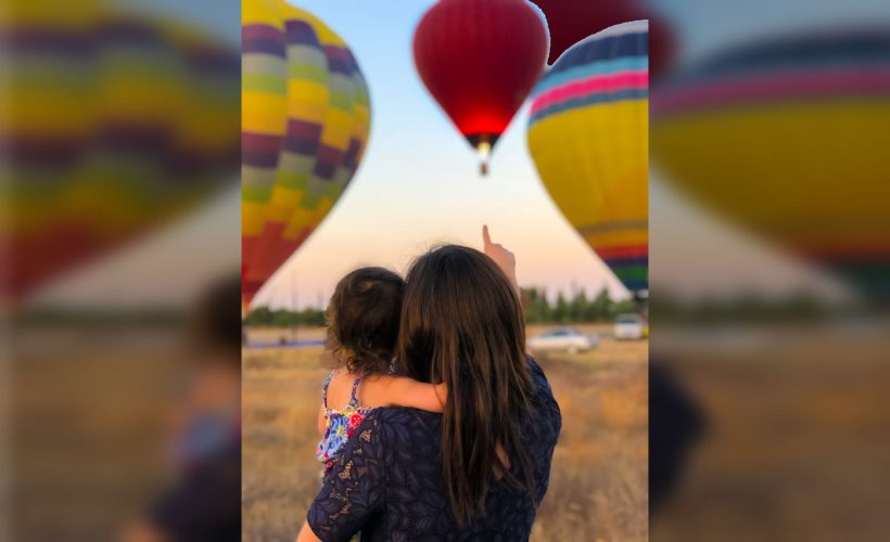 parent and child gaze at hot air balloons